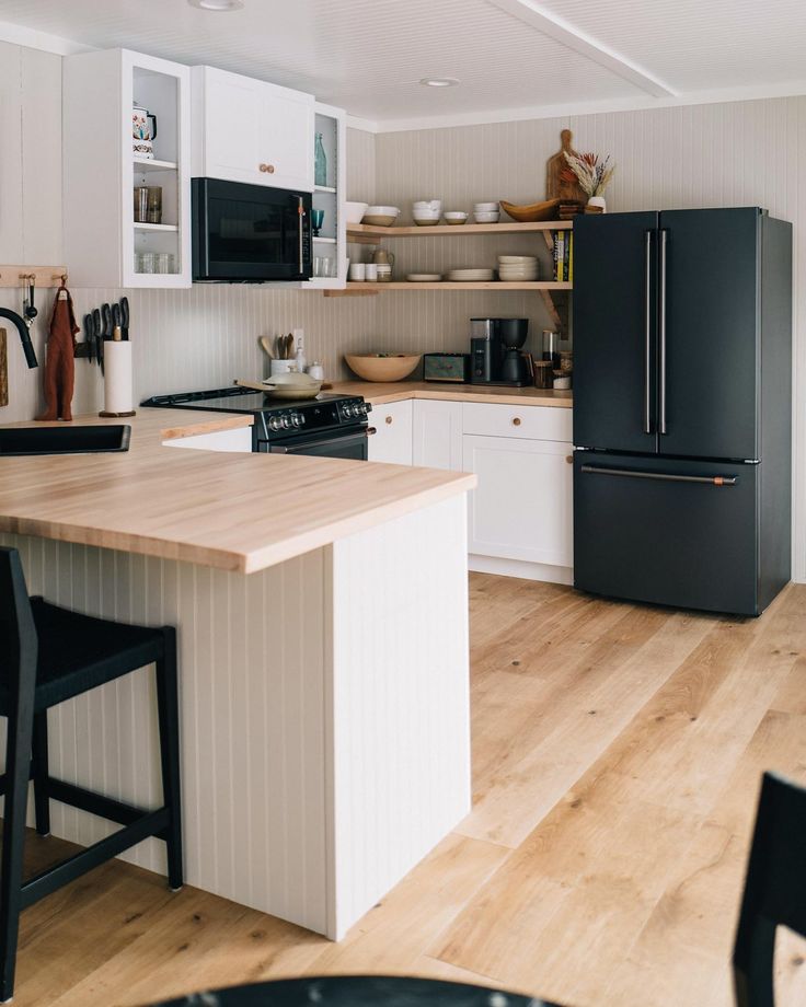 a black refrigerator freezer sitting inside of a kitchen next to a wooden counter top