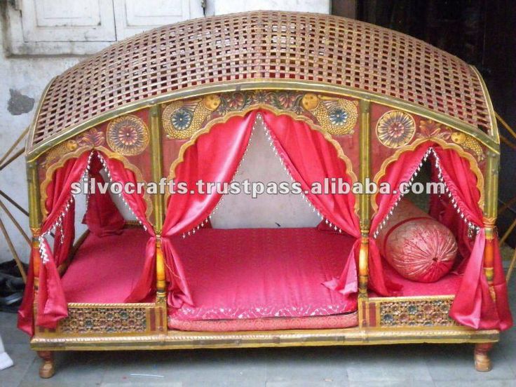 the bed is made out of wood and has pink sheets on it, with red drapes