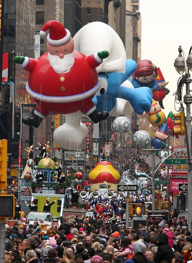 many balloons float in the air as people walk down a city street during christmas time