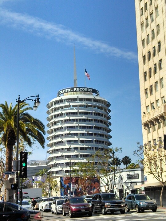 cars are driving down the street in front of a tall building with a flag on top