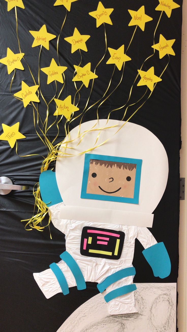 a door decorated with paper stars and a drawing of an astronaut on the outer space