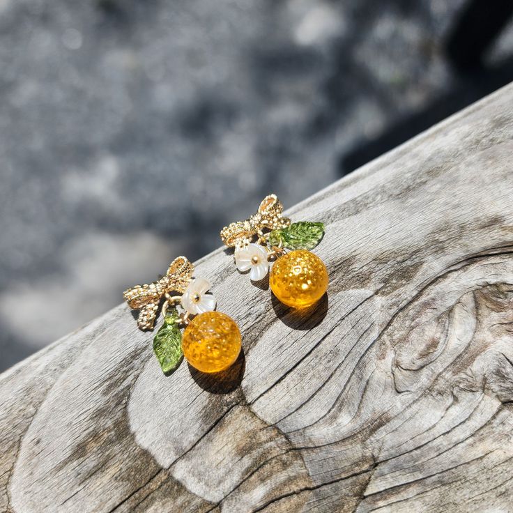 Check out our gold orange earrings! We have the gold and the matte yellow oranges. I love the gold sprinkles! As you walk, they create a radiant sheen on the orange surface. The matte yellow oranges have special texture and a rich yellow color which makes them noticeable. The earrings are made with cute Czech glass oranges, acrylic flowers and 14K gold plated 925s silver lace bow tie studs which are hypoallergenic. Size: approx. 1.27cm x 1.7cm Oranges Fruit, Acrylic Leaves, Gold Sprinkles, Flowers Acrylic, Rain Design, Pearl Accessories, Fruit Jewelry, Fruit Food, Fruit Earrings