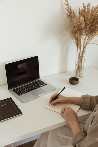 a person sitting at a desk with a laptop, notebook and pen in front of them