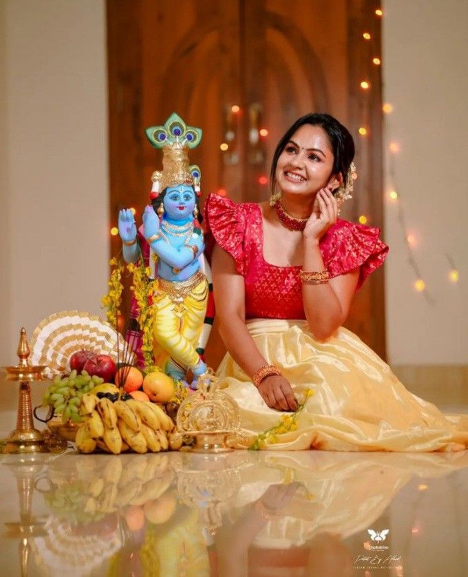 a woman sitting on the floor next to a statue of lord ganeshra and fruit