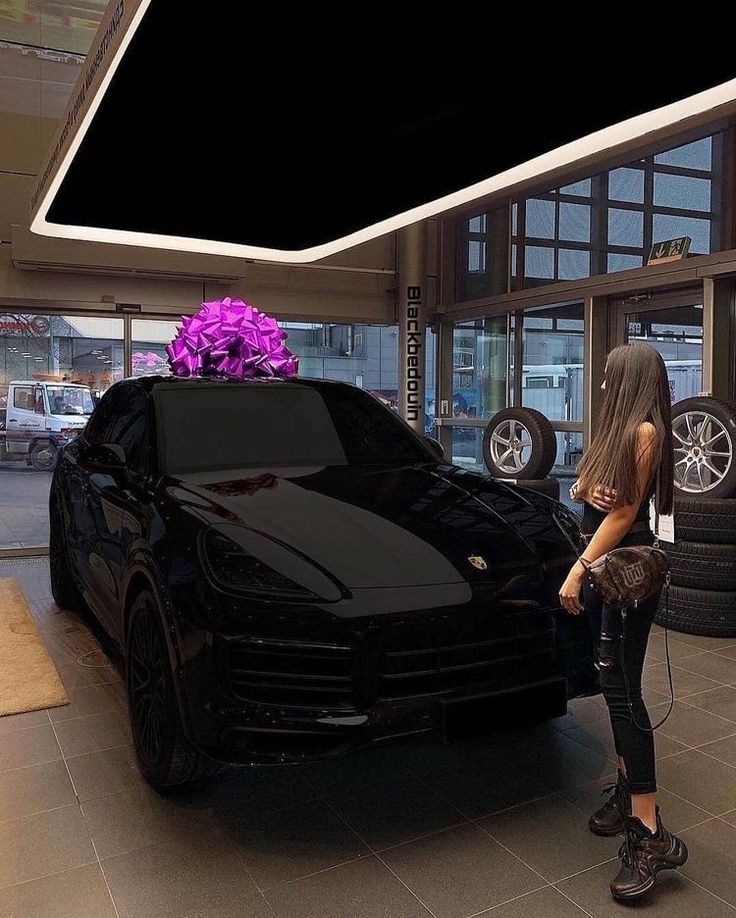 a woman standing next to a black sports car