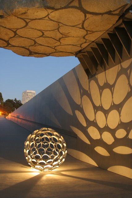 an artistic sculpture is lit up in the evening with its light shining on it's surface