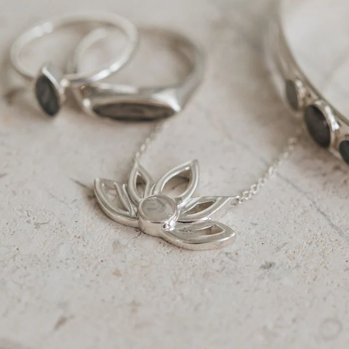 Solidified cremains set in the 5mm circular setting on this stunning and unique .925 Sterling Silver Lotus Flower Cutout Necklace with fixed bails on each side that attach to the chain and an overall size of 24x16mm. The Lotus is a symbol of the beauty that can grow from even the darkest of places, and thus, the love t Spiritual Sterling Silver Necklace With Birth Flower, Timeless Flower Pendant Jewelry Gift, Spiritual Sterling Silver Jewelry With Birth Flower, Sterling Silver Nature-inspired Necklace For Anniversary, Sterling Silver Gemstone Necklace For Meditation, Spiritual Polished Wedding Necklaces, Sterling Silver White Gold Birth Flower Necklace, Timeless Silver Flower Pendant Jewelry, Delicate Silver Necklace For Meditation