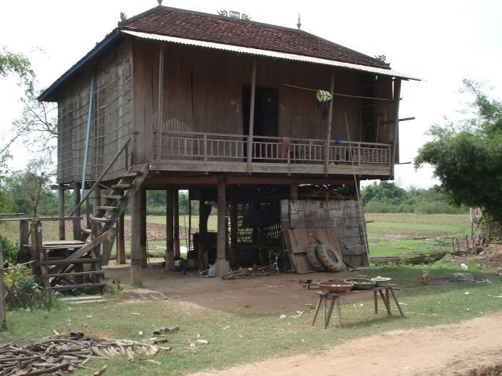 an old wooden house sitting on the side of a dirt road