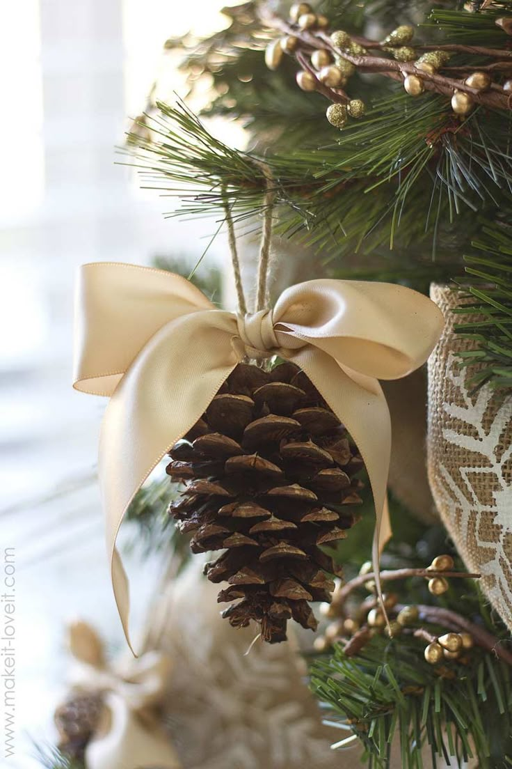 a pine cone ornament hanging from a christmas tree with a bow on it