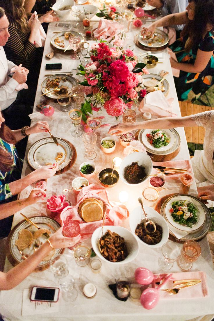 a group of people sitting around a table with plates and bowls of food on it