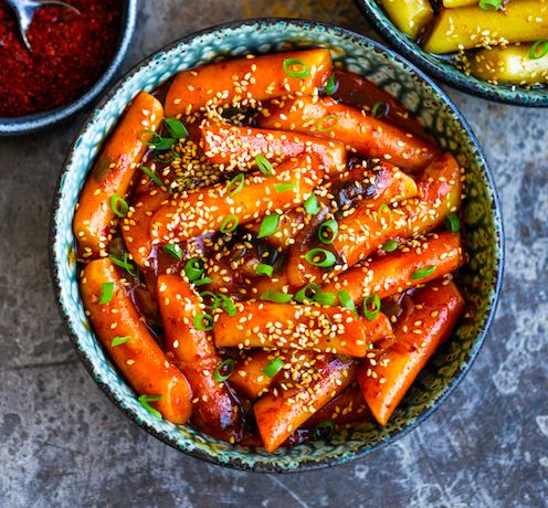 two bowls filled with carrots covered in sesame seeds