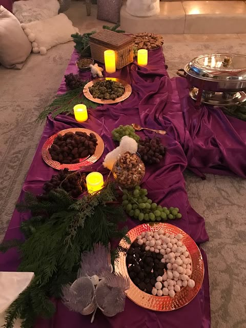 the table is set up with candles and plates full of food, along with other foods