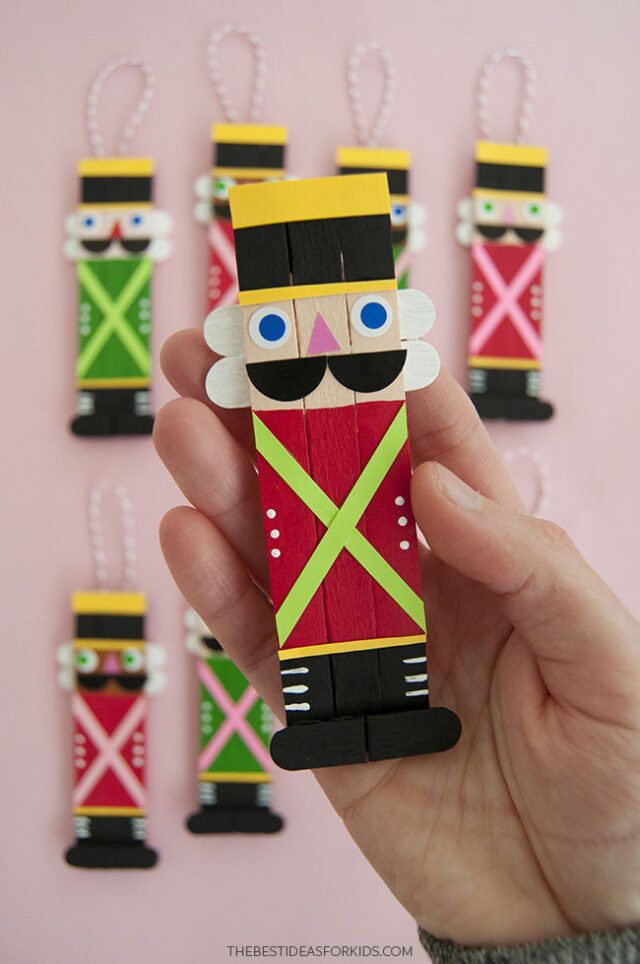 a hand holding a small wooden nutcracker ornament