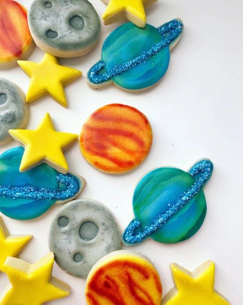 some cookies that have been decorated to look like planets and the stars are painted on them