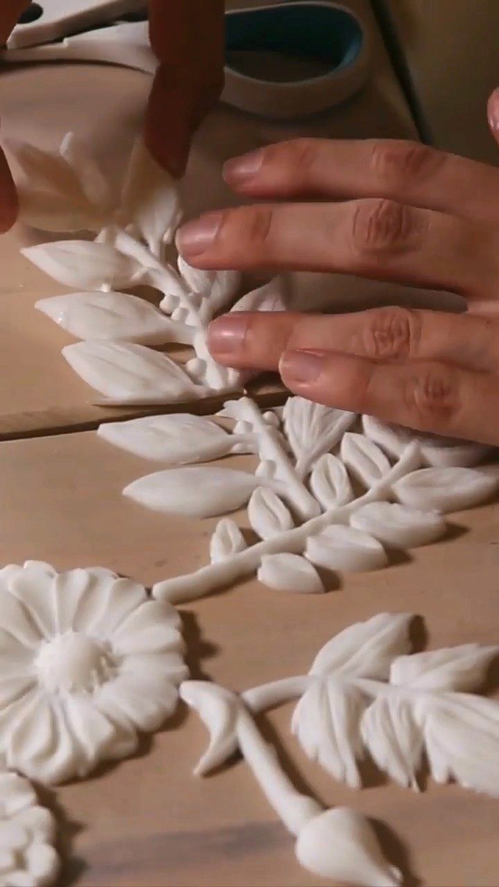 two hands are working on an intricately designed piece of art that looks like flowers