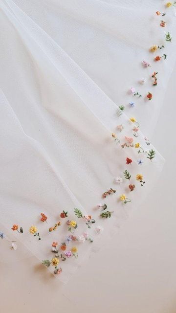 white fabric with flowers on it laying on top of a tablecloth covered in glass beads