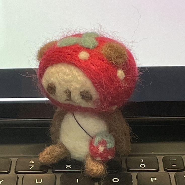 a small stuffed animal sitting on top of a laptop keyboard