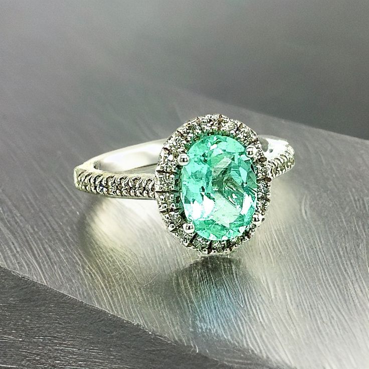 an oval shaped ring with a green center surrounded by white diamonds on a metal surface