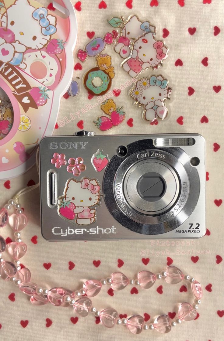 a hello kitty camera sitting on top of a table next to some heart shaped objects