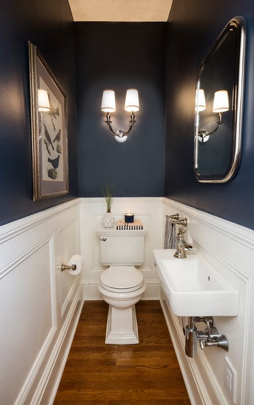 a white toilet sitting next to a sink in a bathroom under two framed pictures on the wall