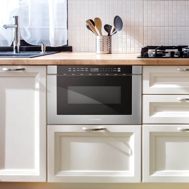 a kitchen with white cabinets and an oven in the middle is seen from across the room