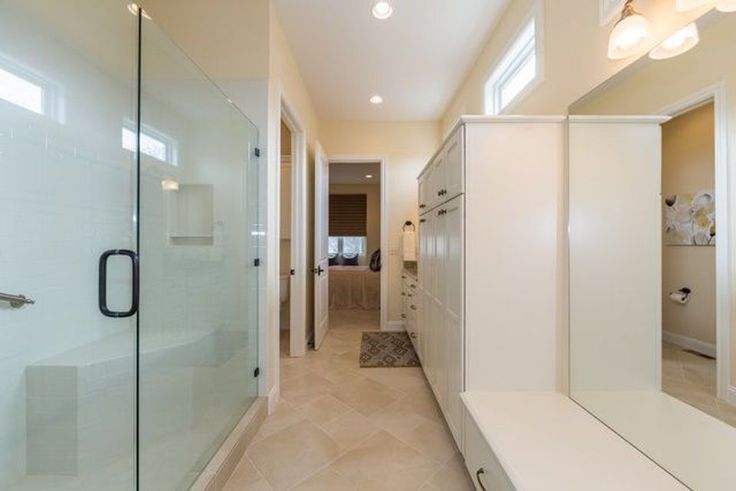 a bathroom with a walk in shower next to a white sink and counter top under two lights