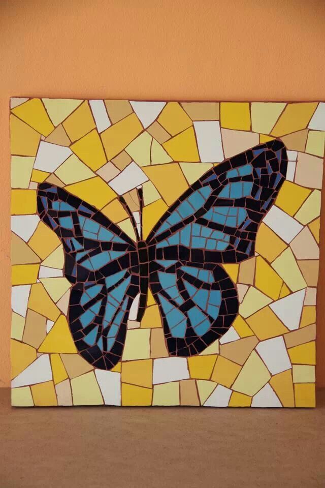 a blue butterfly painted on a yellow and white mosaic tile wall hanging in front of an orange wall