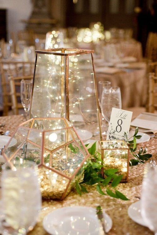 the table is set up with plates, glasses and vases for guests to enjoy