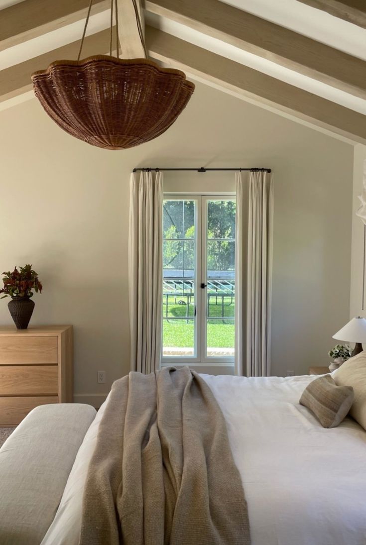 a bedroom with a bed, dresser and large glass door that leads to a lush green yard