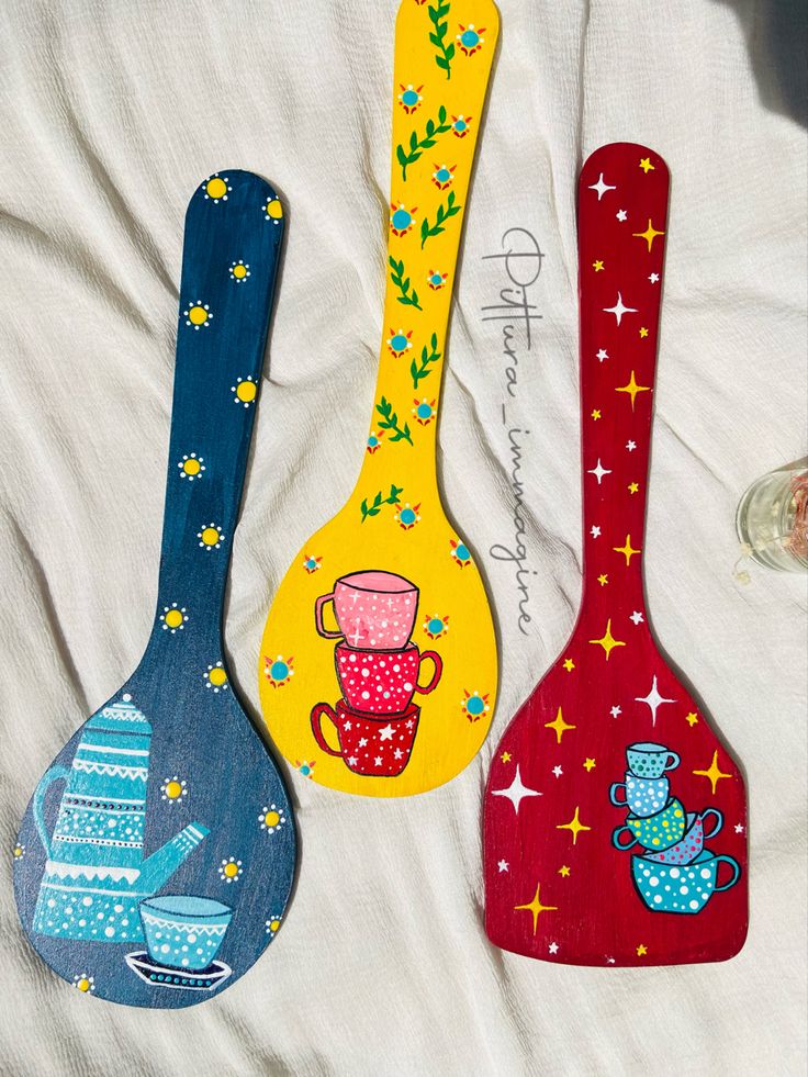 three wooden spoons with designs on them sitting next to each other in the bed