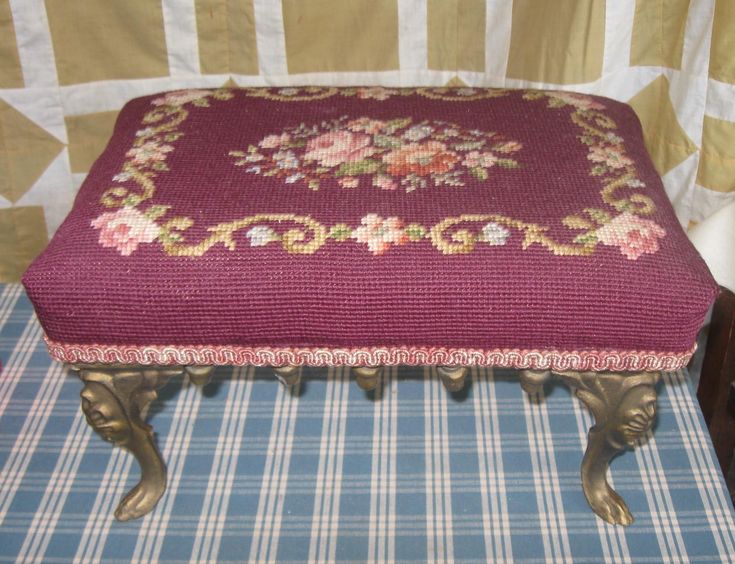 a foot stool with a floral design on it and a plaid tablecloth behind it