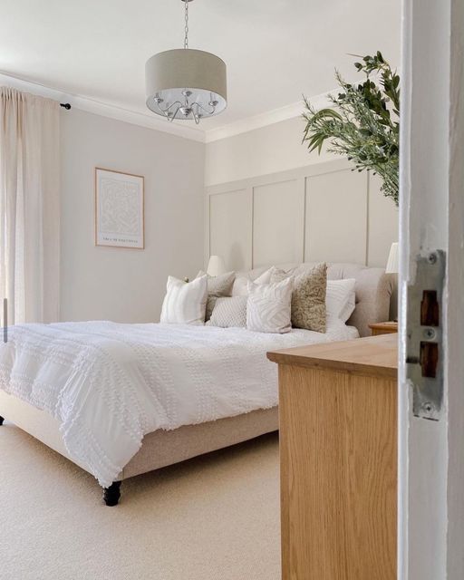 a large white bed sitting in a bedroom next to a wooden dresser and window sill