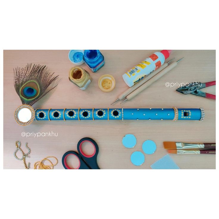 an assortment of arts and crafts items displayed on a wooden table with scissors, tape, glue, markers, beads, feathers, pens, and other crafting supplies