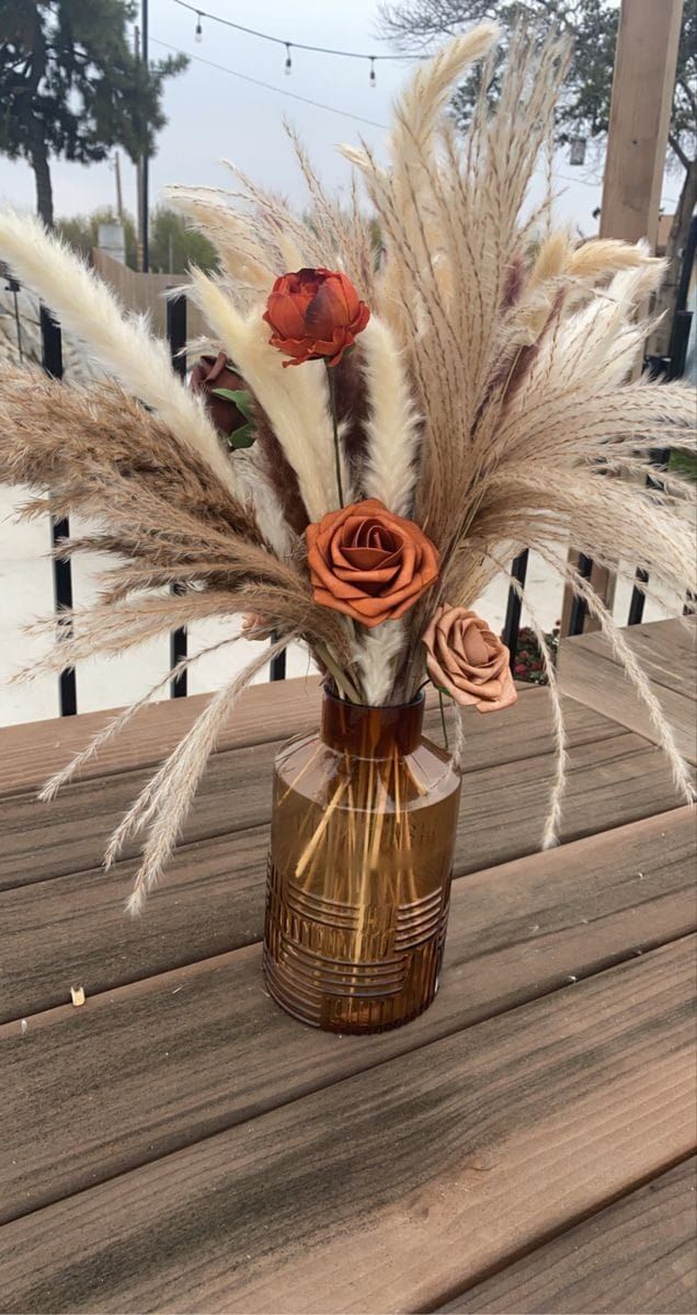 a vase filled with dried flowers on top of a wooden table