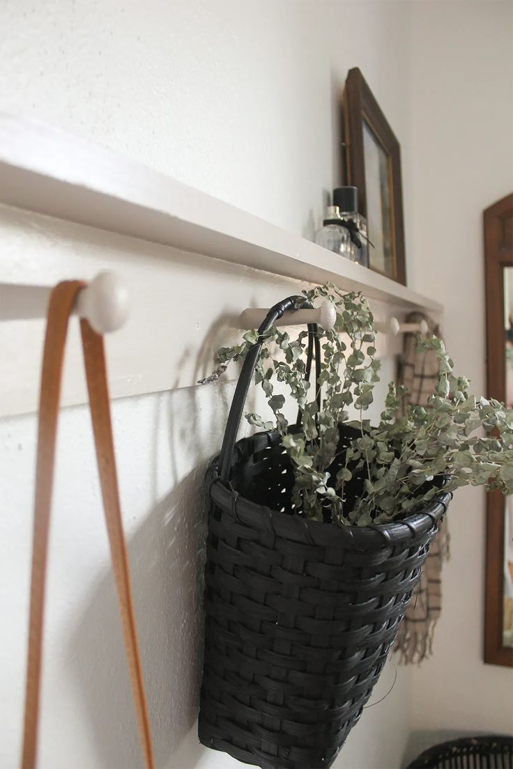 Stylish white DIY peg rail shelf with attached to white wall with purse, basket and scarf hanging from it. A modern style shaker peg rail with simple decorations. Picture frame and perfume bottles on top of shelf. Diy Peg Rail, Popcorn Paint, Peg Rail Shelf, Shaker Peg Rail, Peg Shelf, Rail Shelf, Awkward Corner, How To Make Floating Shelves, Fresh Popcorn