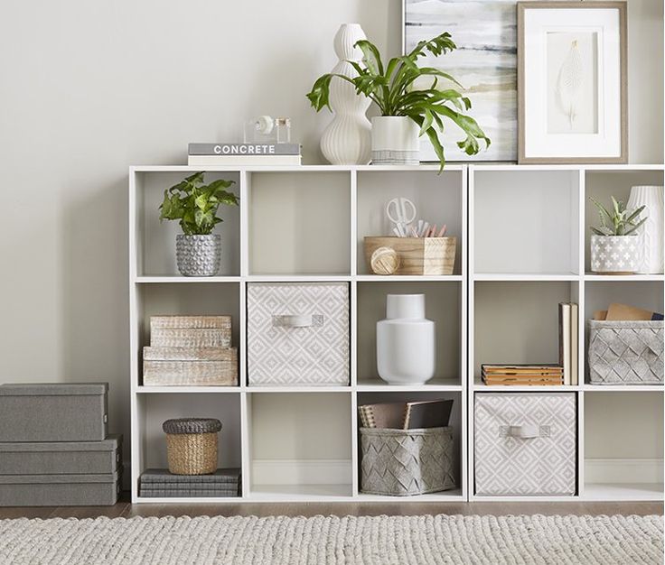 a white shelf filled with lots of different types of baskets and vases on top of it