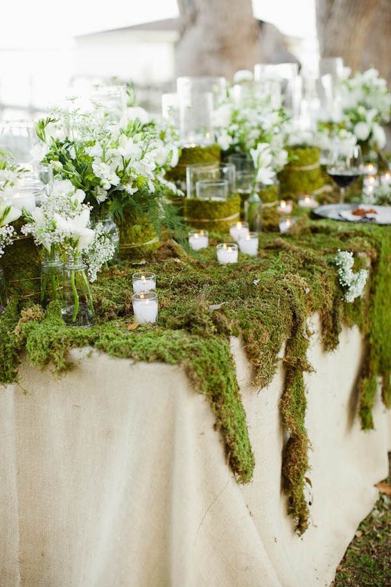 moss covered tables with white flowers and candles