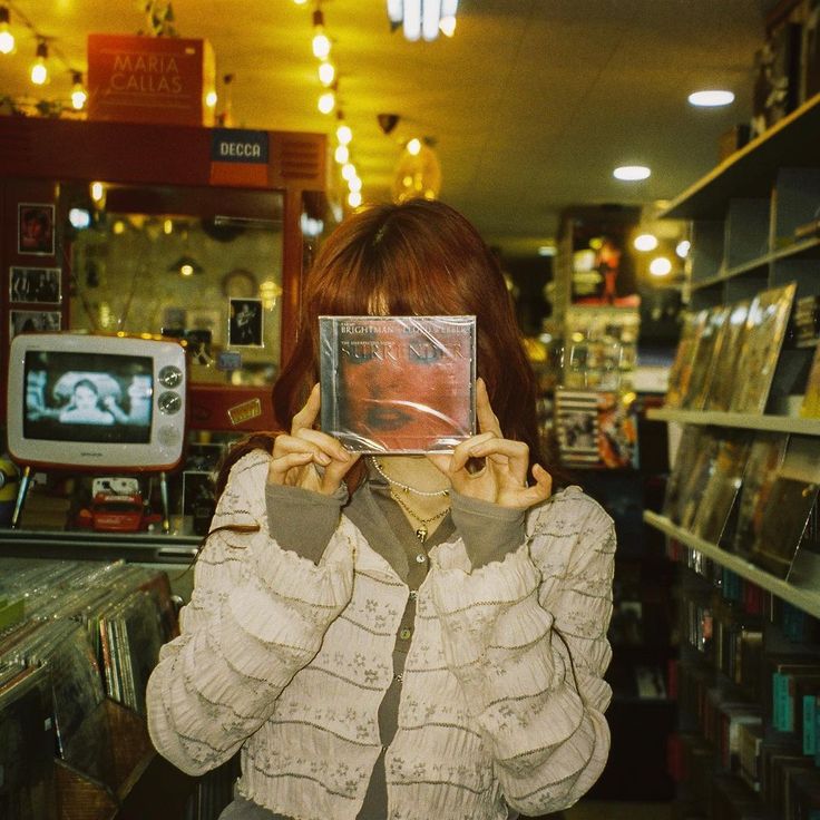 a woman holding up a cd in front of her face