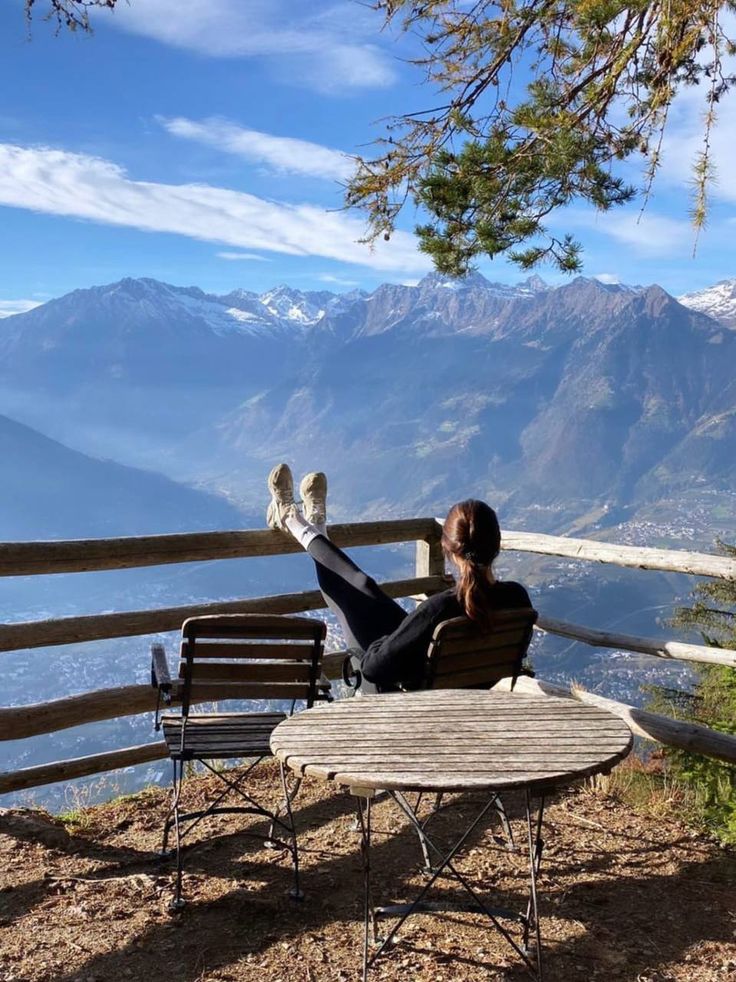 a woman sitting on top of a wooden bench