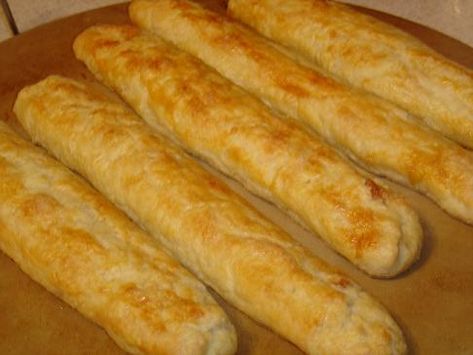 bread sticks are lined up on a cutting board