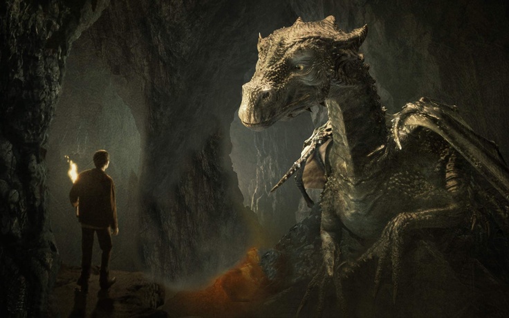 a man standing next to a dragon in a cave at night with the light on