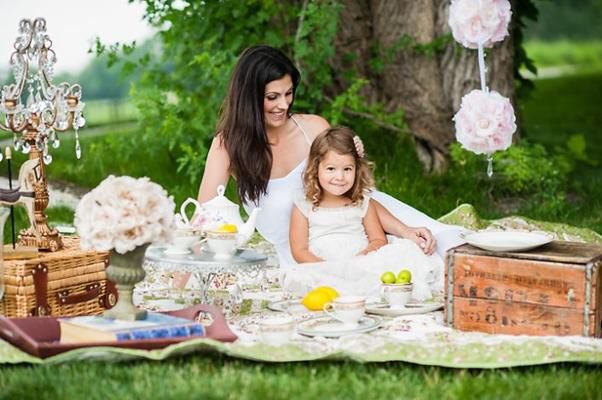 a mother and daughter having tea outdoors in the grass with lemons on the table