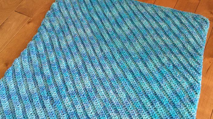 a blue knitted blanket laying on top of a wooden floor