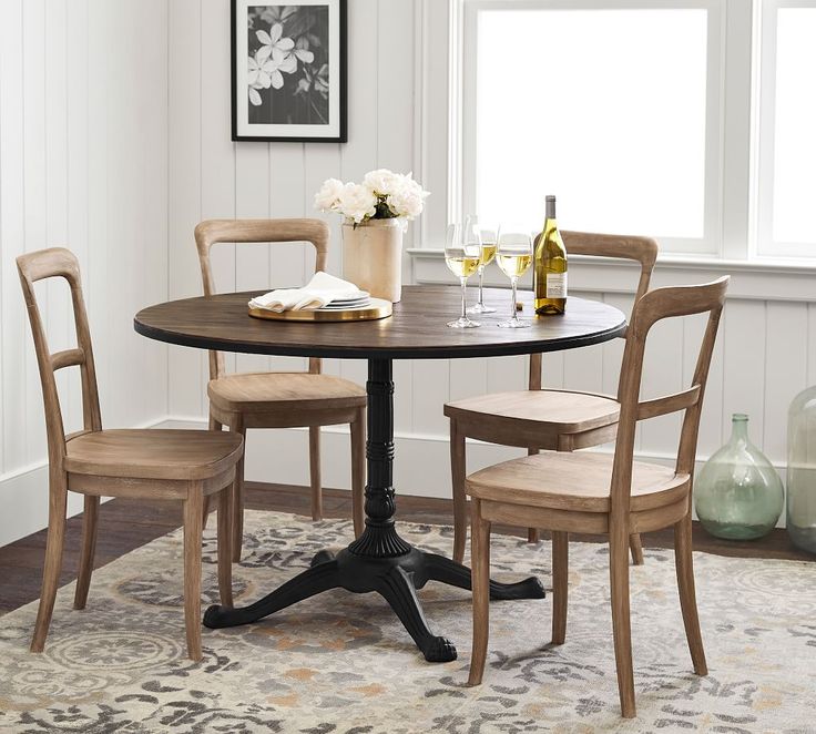 a dining room table with four chairs and a wine bottle on the table next to it