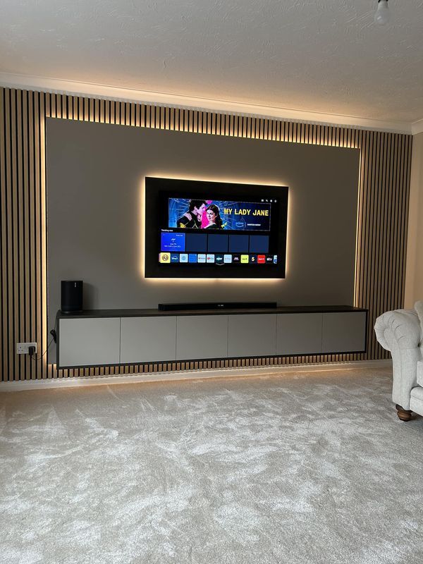 a large flat screen tv mounted on the wall in a living room with white carpet