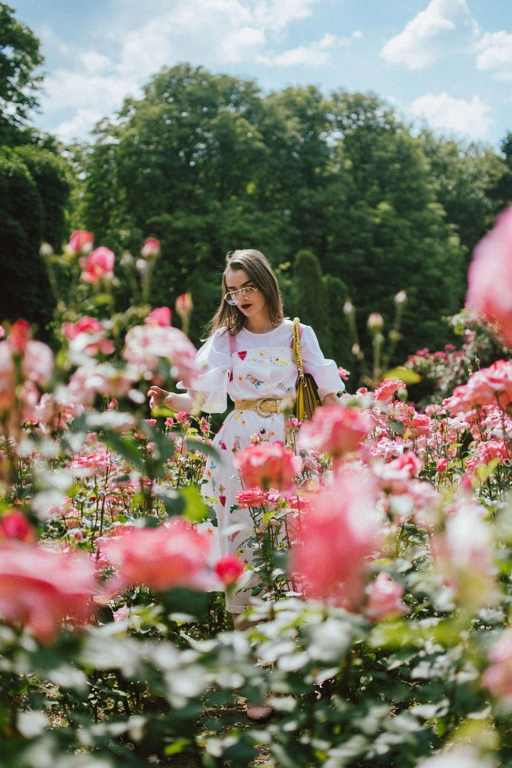 a woman standing in a field full of pink flowers