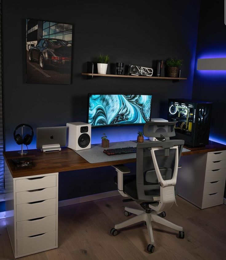 a desk with a monitor and speakers on it in a room that is lit up