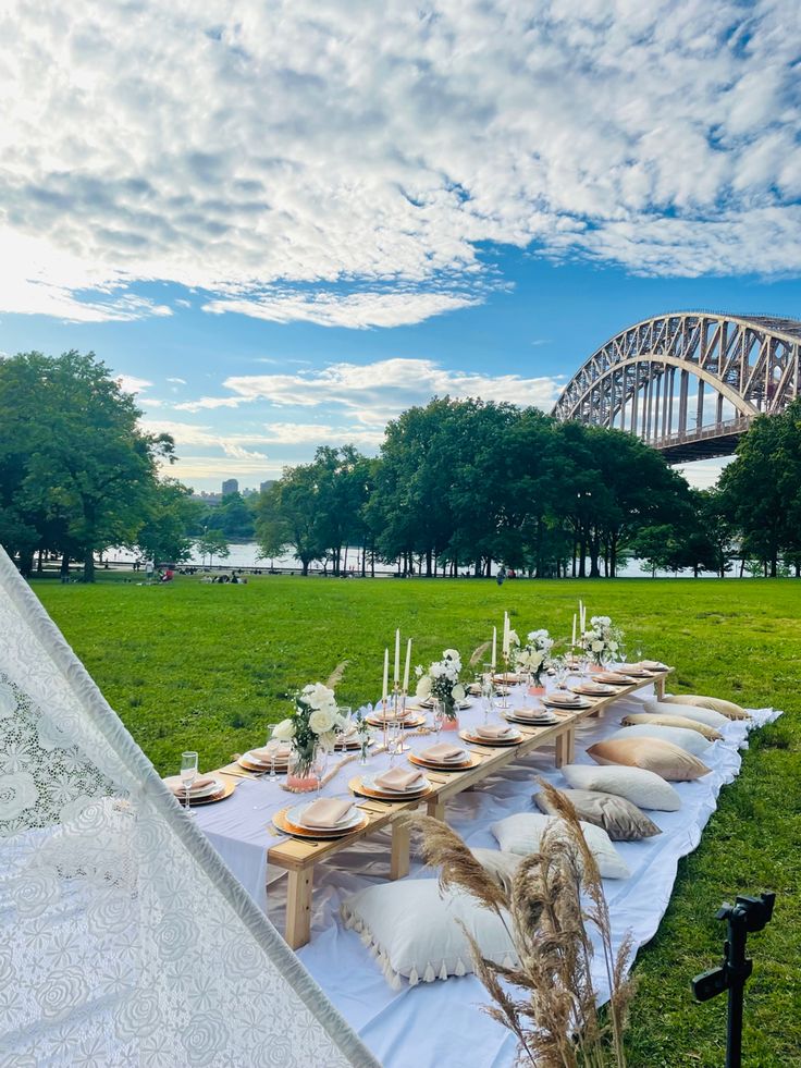 a long table set up with plates and place settings in front of the sydney harbour bridge