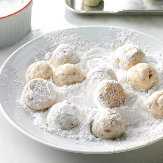 a white plate topped with powdered donuts next to a container of doughnuts