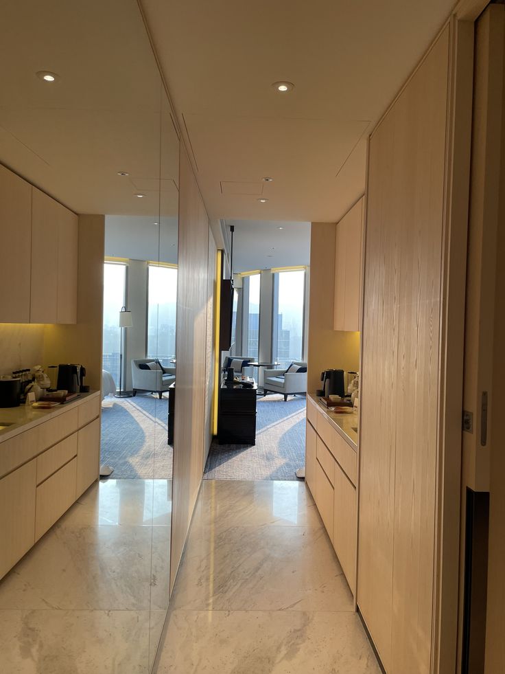 an empty hallway leading to a living room and dining area with large mirrors on the wall